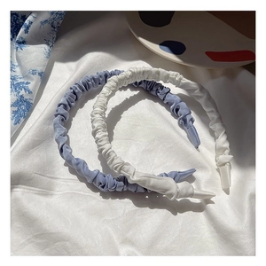 Detail of blue and white pleated satin headbands on soft fabric background