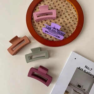 Five candy-colored matte rectangular hair claws on a woven tray for women