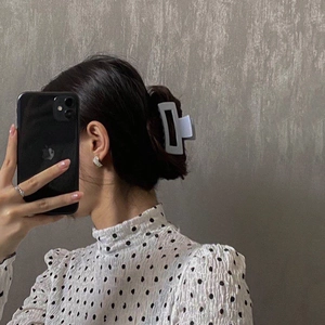 Detailed close-up of a white rectangular matte hair claw clip on dark hair accessory