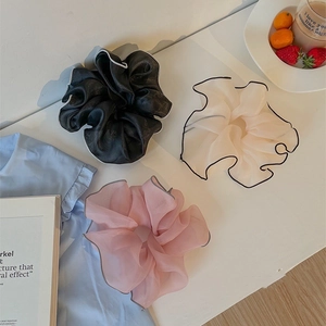Three large organza scrunchies in black, cream, and pink with contrast trim on white desk