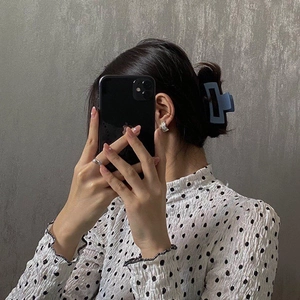 Close-up of a matte light blue hair claw clip used in a stylish hair bun hairstyle