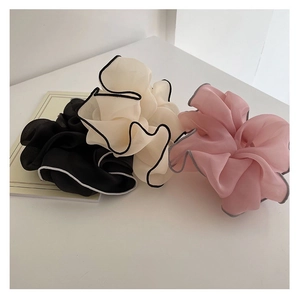 Close-up of three mesh hair scrunchies with contrast edges in black, cream, and pink