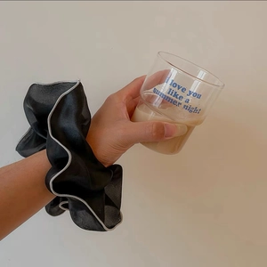 Close-up of large black organza scrunchie with white wavy edge detail on wrist