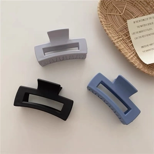 Three-piece matte rectangular hair claw clips in grey, black, and blue tones