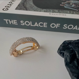 Detaillierte Nahaufnahme einer goldfarbenen Haarspange mit funkelnden Strasssteinen und Federclip