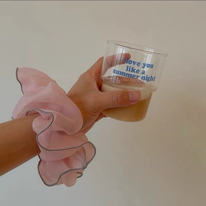 Detail of pink organza scrunchie with grey edge worn on wrist for hair styling