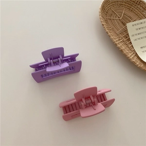 Detail of pink and purple matte claw clips with rectangular hollow design for hair