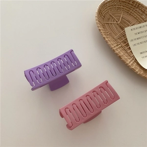 Detail of matte purple and pink square hair claws with wavy hollow design