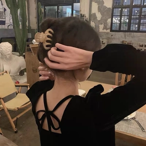 Detail showing a matte coffee-colored claw clip used for styling a messy bun on a woman