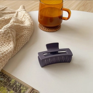 Close-up of a matte purple rectangle hair claw clip on a stylish table setting