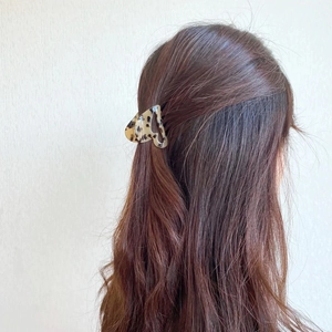 Macro detail of heart-shaped leopard print claw clip in brown acetate material