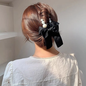 Elegant black satin bow hair claw with pearls shown on a woman from a back view