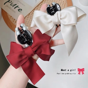 Elegant satin bow hair claw with pearl accents in cream and deep red for women