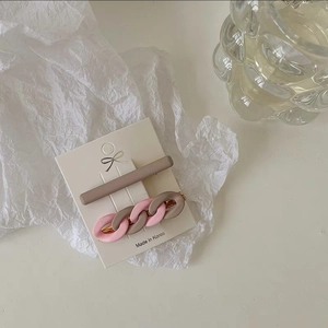 Close-up of matte brown hair clip and pink chain hair accessory on a display card