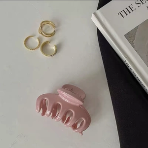 Detail of soft pink matte hair claw clip and golden textured accessory rings set