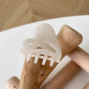 Minimalist cream white acetate heart hair claw clip on a natural wooden branch display