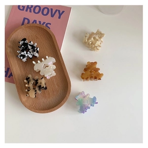 Close-up of colorful acetate mini bear hair claws and heart clips on a wooden tray