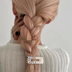Floral tortoiseshell hair claw clip styling a blonde braid in a minimalist setting