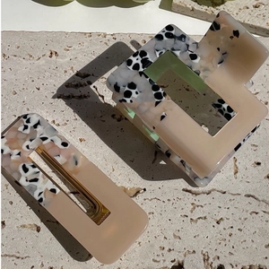 Detail of a medium hair claw clip and barrette set in beige and cow pattern resin