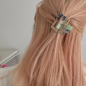Detail view of a medium rectangular leopard print hair claw clip on pink blonde hair
