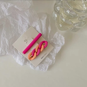 Detail view of pink and orange chain style hair clips set on white branding card