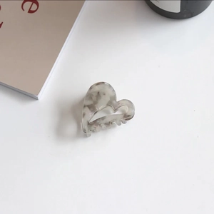 Detailed macro view of heart-shaped marble acetate hair claw clip with metal spring