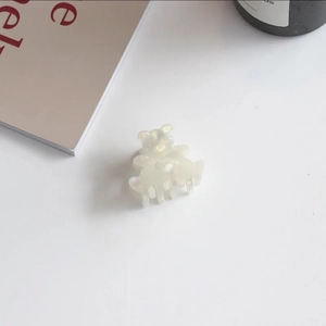 Detail view of mini bear-shaped pearl white acetate hair claw clip for hair styling