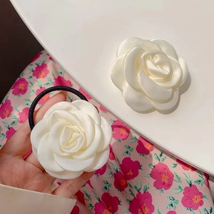 Detail of white camellia hair tie showing layered satin fabric and elastic cord
