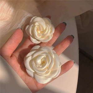 Detail of cream white fabric camellia hair clips with elegant satin texture and petals