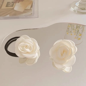 Close-up of elegant ivory camellia flower hair ties with a soft silk satin texture