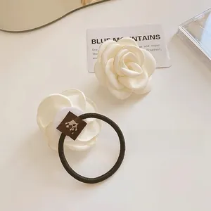 Detail view of elegant white silk camellia flower hair tie and hair clip set for women