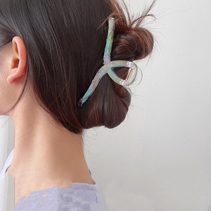 Détail d'une grande pince à cheveux en résine irisée pour une coiffure élégante relevée
