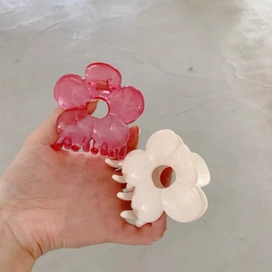 Detail showing pink jelly and cream white floral claw clips held in hand