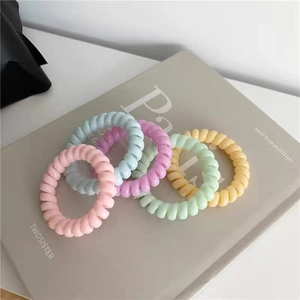 Fünf Haargummis in Macaron-Farben im Spiraldesign auf einem minimalistischen Magazinheft