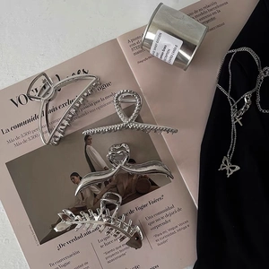 Close-up of assorted silver metal hair claws and a butterfly pendant chain on a magazine
