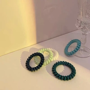 Detailaufnahme bunter Spiralkabel-Haargummis in fünf sommerlichen Bonbonfarben
