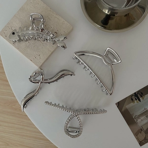 Detailed view of four silver metal claw clips in minimalist and fishbone shapes