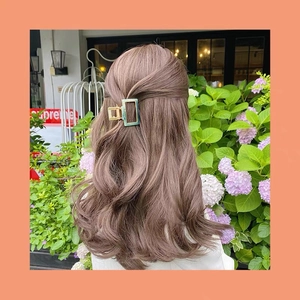 Vintage geometric acetate hair claw with gold metal base shown in an elegant outdoor setting