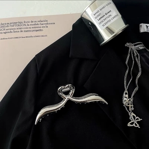 Silver wavy heart hair claw clip and butterfly cross necklace on black fabric blazer