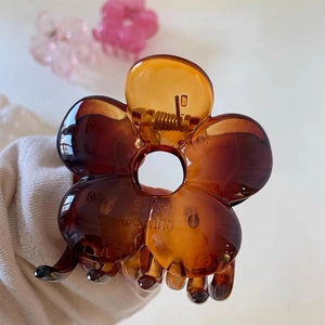 Macro view showing the translucent amber flower hair claw clip with detailed petal design