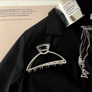 Minimalist silver metal hair claw clip displayed on a chic black blazer with fashion props