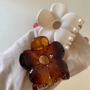 Close-up of flower hair claws in cream white and translucent amber on soft fabric