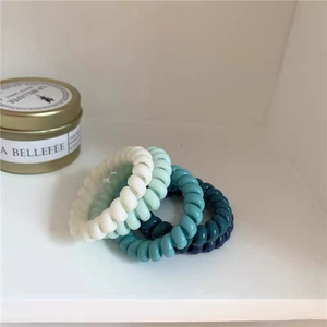 Detail von vier bunten Spiral-Haargummis in minimalistischen Pastell-Bonbonfarben