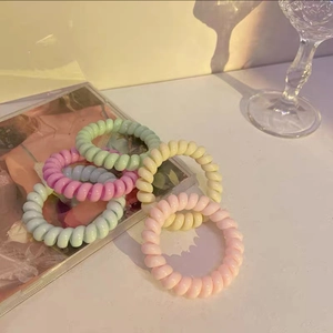 Detailaufnahme von Spiral-Haargummis in Macaron-Farben in ästhetischer Umgebung