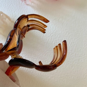 Macro shot of dark brown tortoiseshell hair claw showing metal spring and grip space