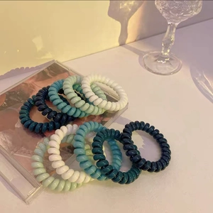 Nahaufnahme bunter Spiral-Haargummis in Blau und Grün auf einer klaren Oberfläche