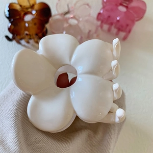 Close-up of large resin flower hair clips in creamy white, amber, and pink tones