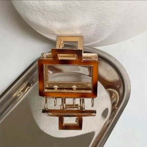 Detail of vintage acetate hair claw clip with brown tortoiseshell and gold metal frame