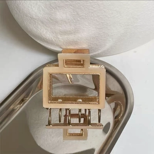 Macro view of cream acetate rectangular hair claw with gold metal frame detail