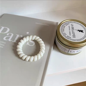 Weißer spiralförmiger Telefonkabel-Haargummi auf grauem Magazin für minimalistischen Look